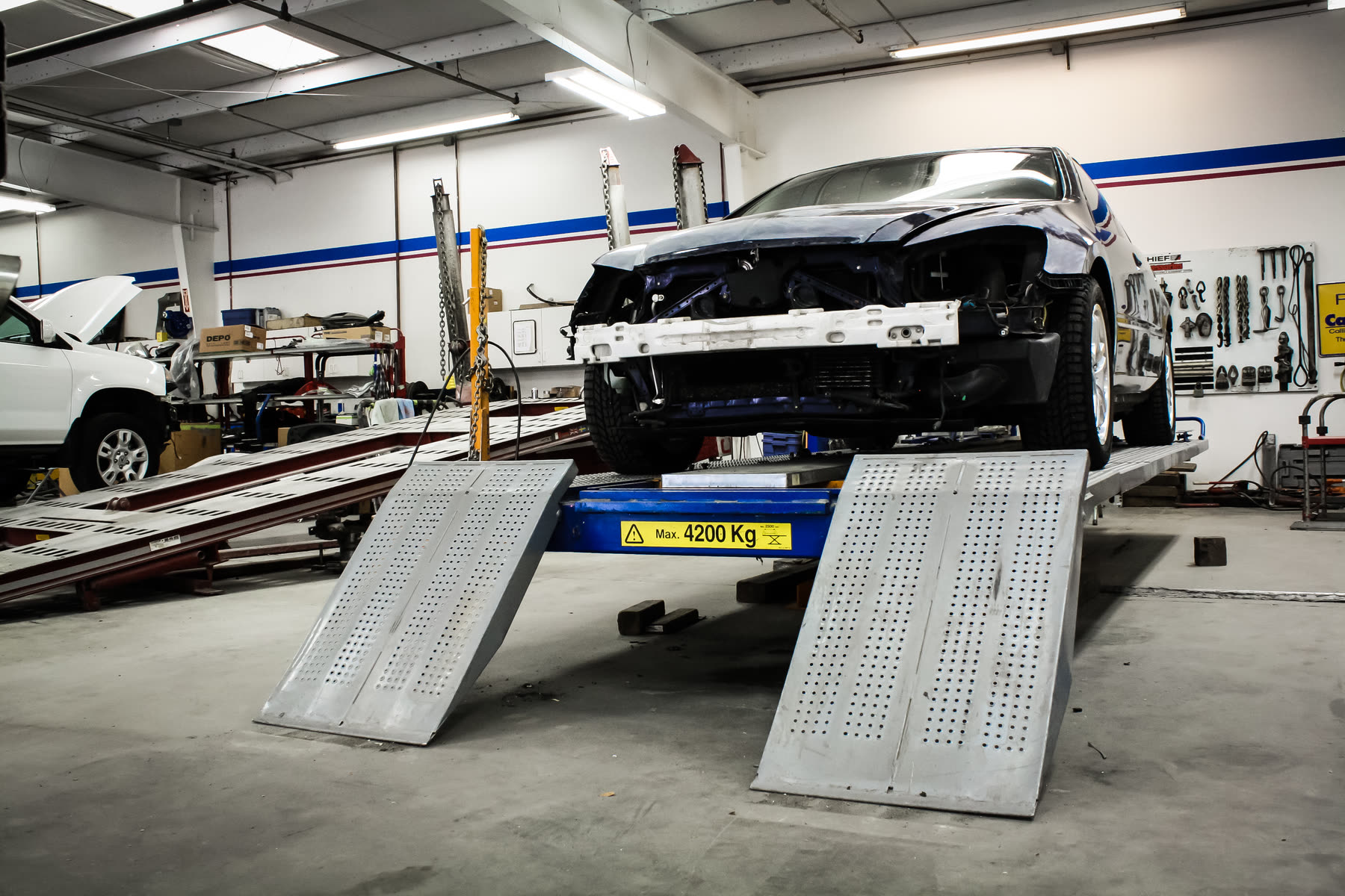 A vehicle raised on the frame bench inside the California Color shop.